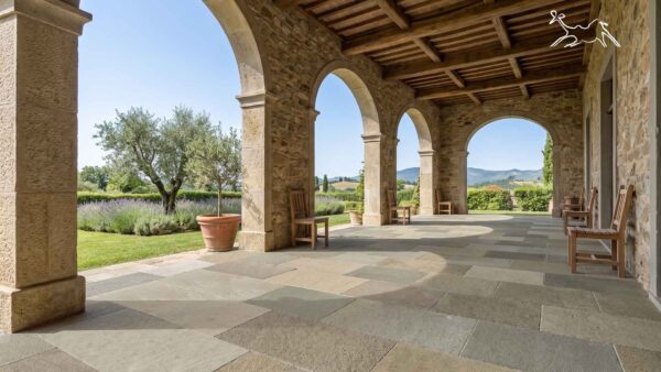 Pavimentazione in pietra naturale per portico esterno di villa in Toscana con archi in pietra, lastre in pietra naturale e finitura antiscivolo per terrazze e giardini.