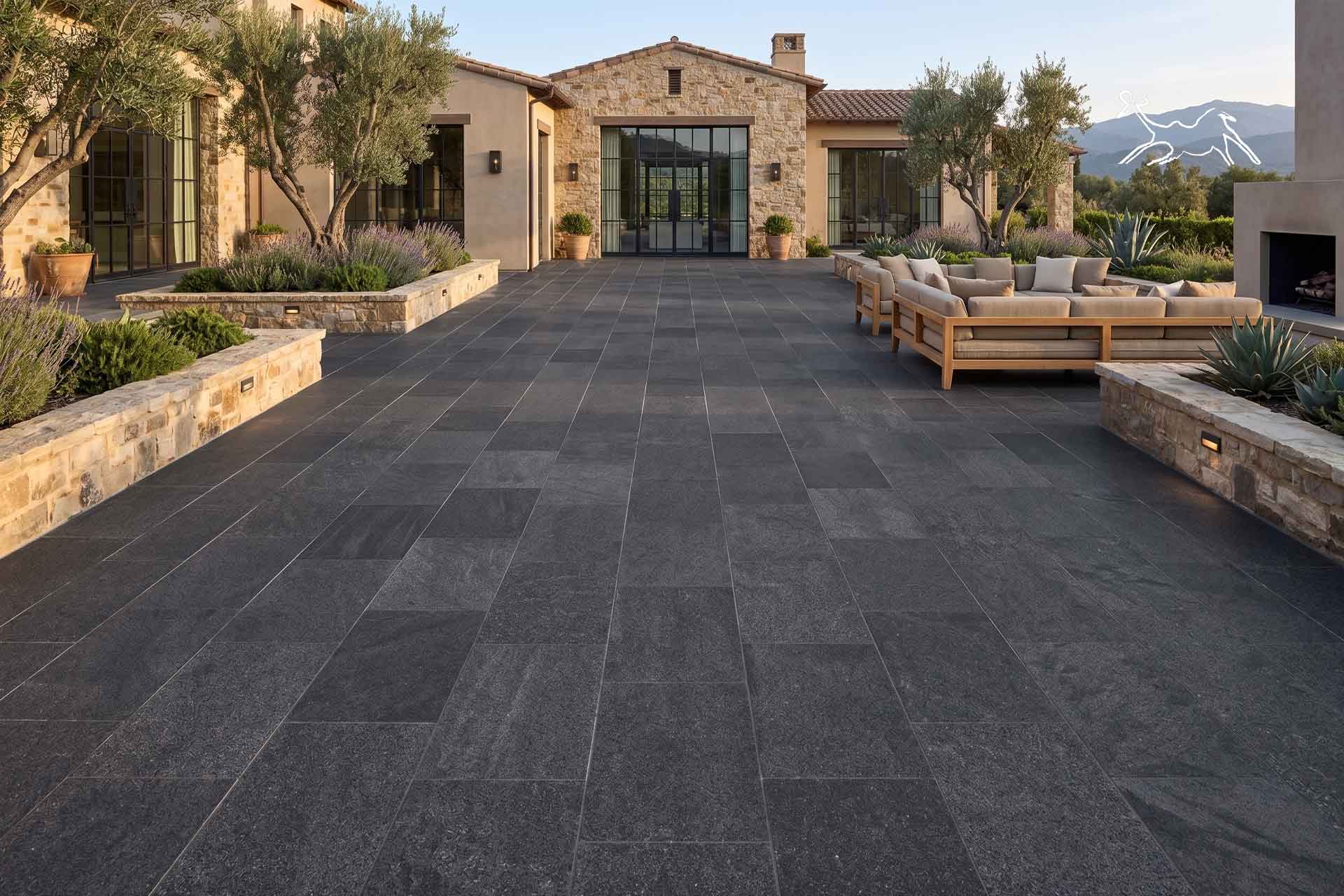 Ampia pavimentazione esterna in pietra naturale scura per il cortile di una villa con fioriere e muri in pietra a Padova